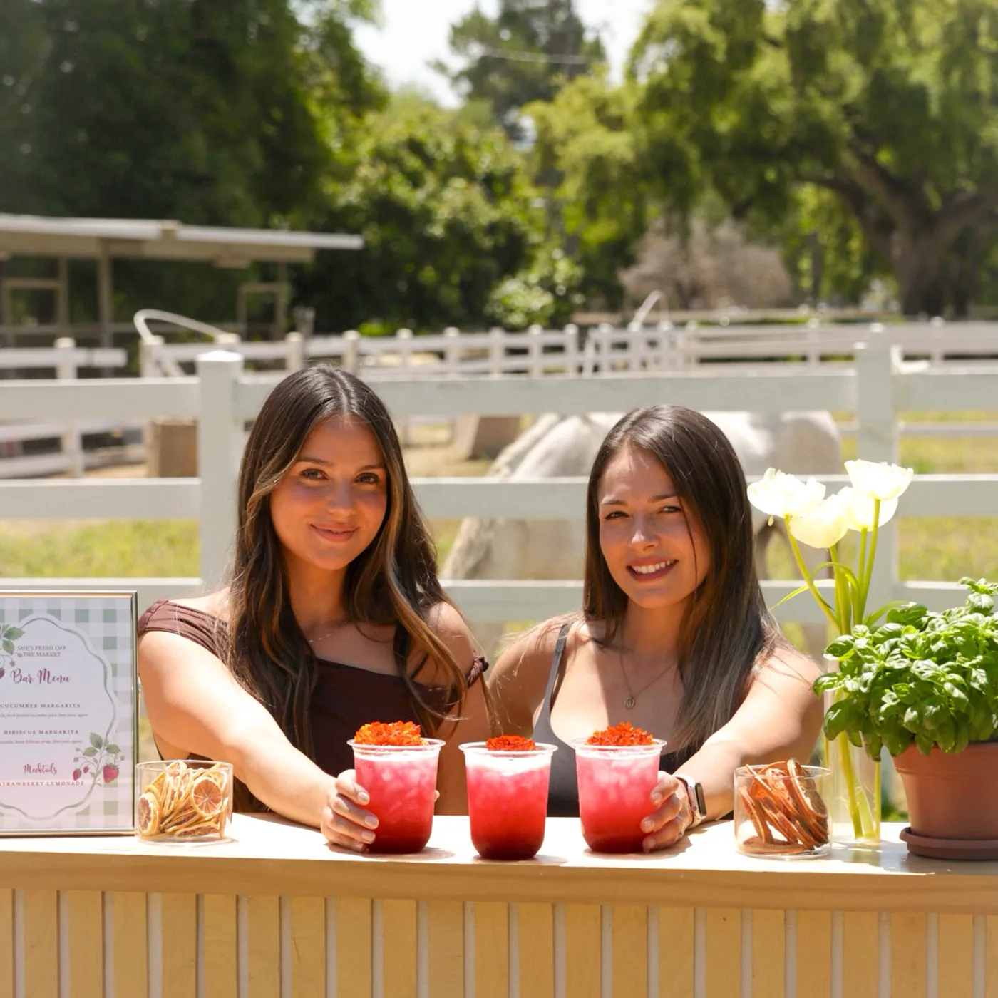 Two With A Twist bartenders behind their bar at a ranch, three finished cocktails on the counter